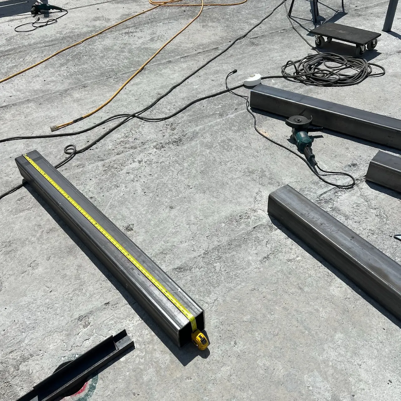 Steel box sections measured and laid out for fabrication on a worksite
