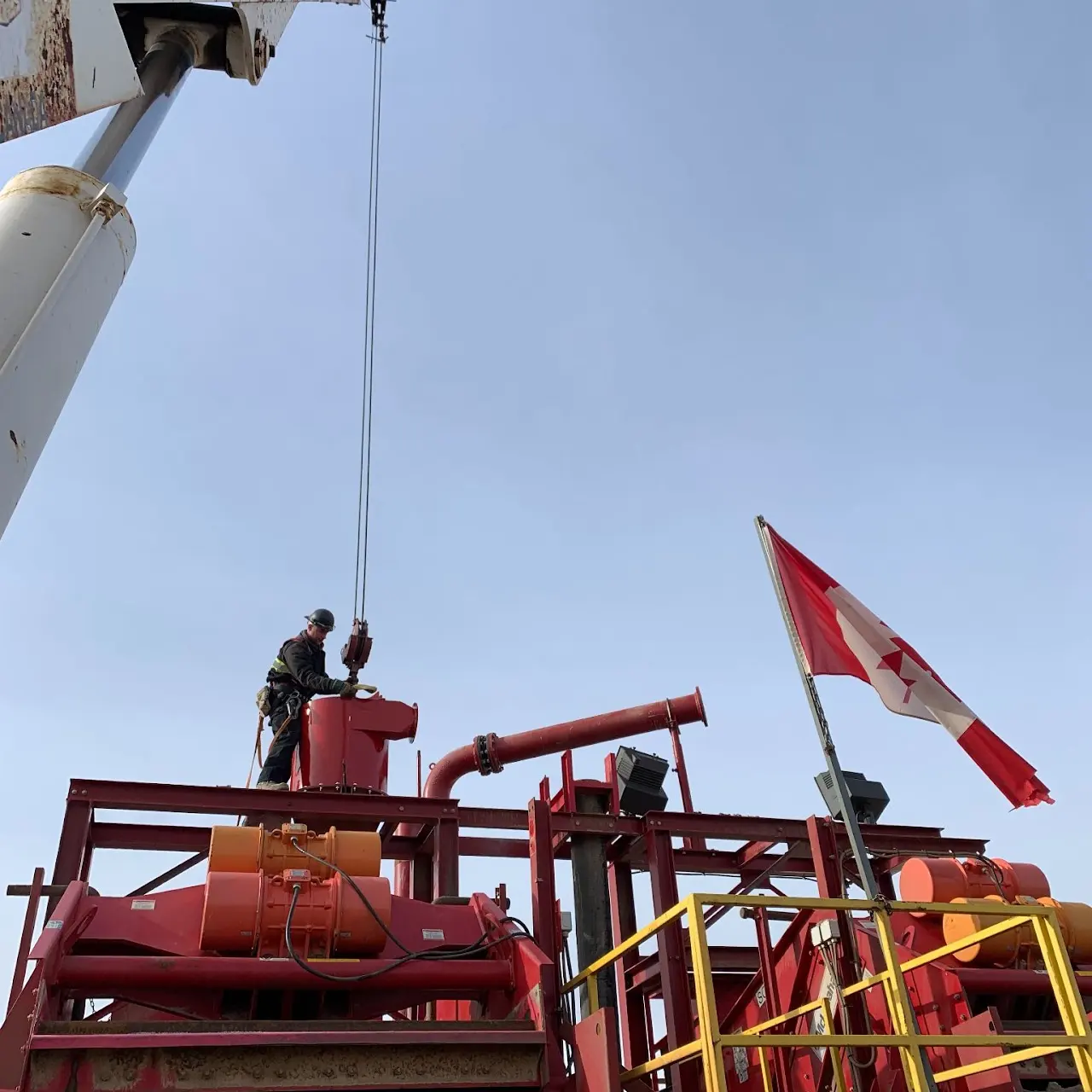 Worker in an elevated red work platform beside industrial equipment