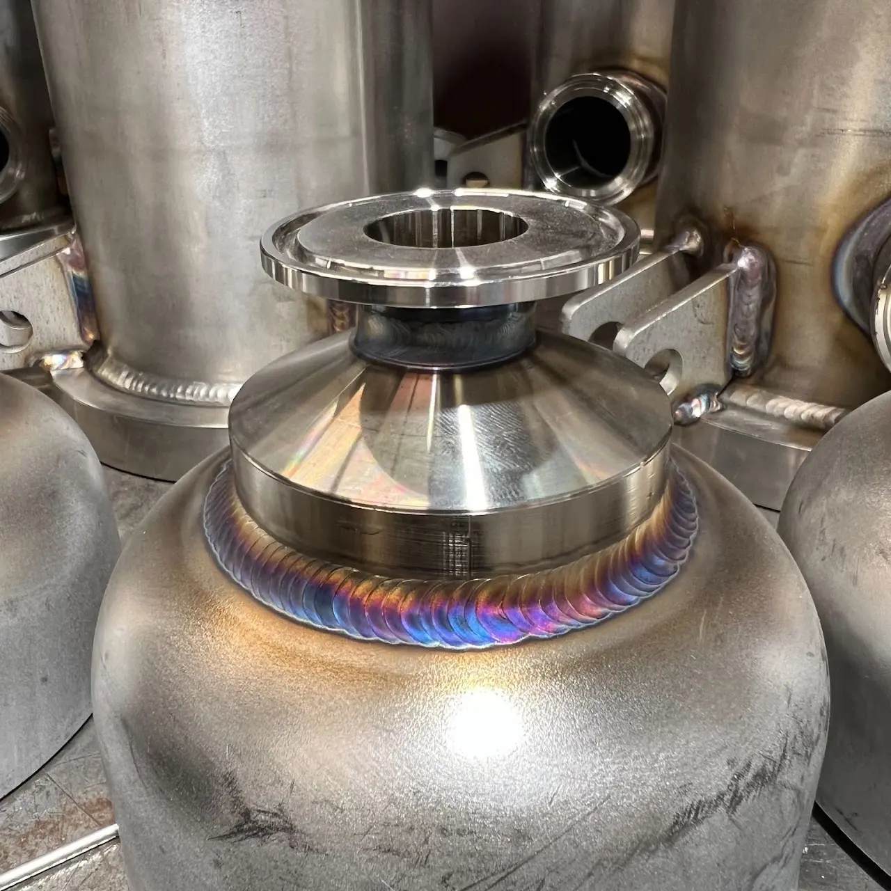 Close-up of a welded metal vessel with a continuous weld around its neck